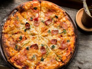 top view photo of pepperoni pizza beside brown cup filled with yellow liquid and ice cubes